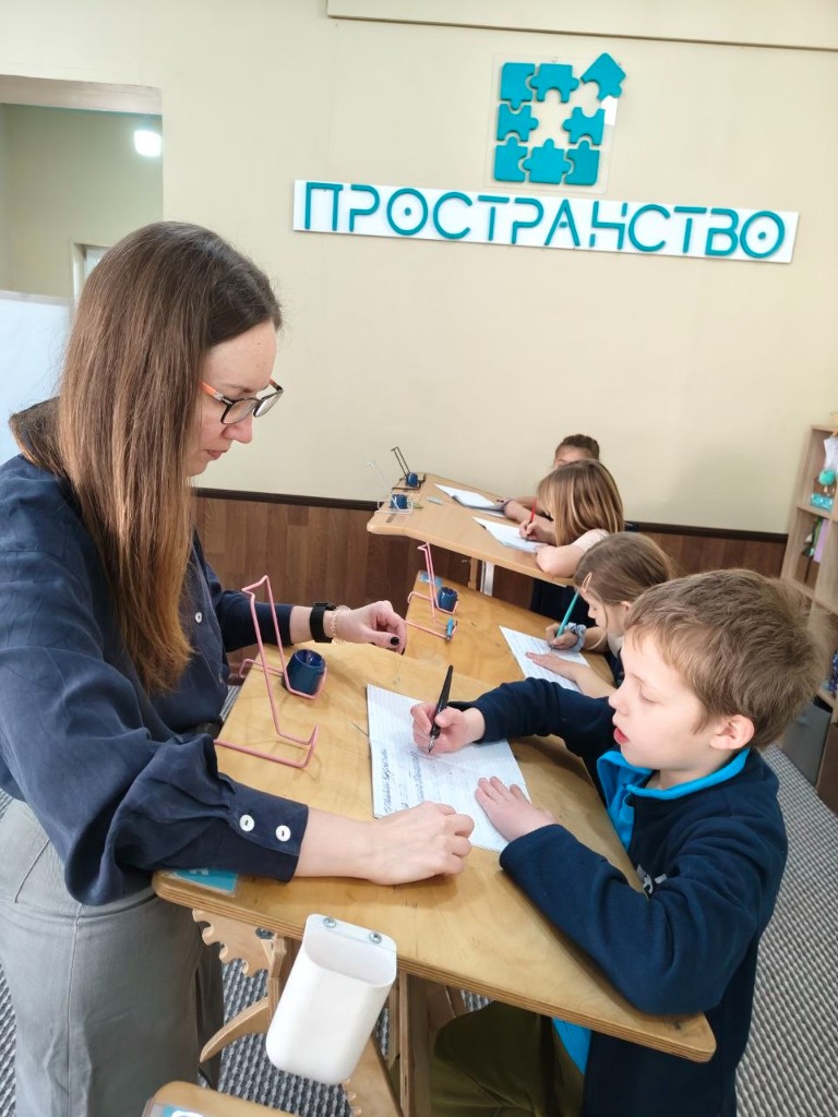Дети занимаются за конторками с наставником в школе «Пространство»