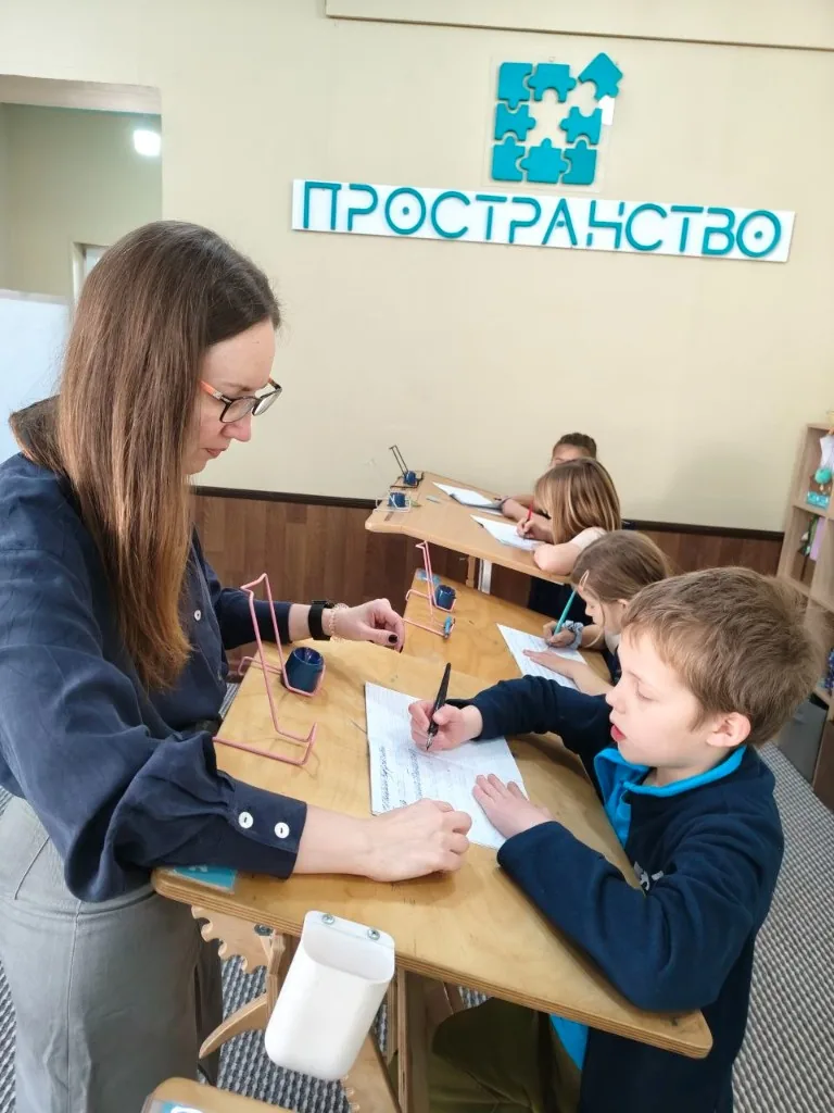 Дети занимаются за конторками с наставником в школе «Пространство»
